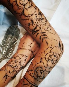 a woman's leg with flowers and feathers on it, next to a feather