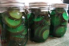 four jars filled with pickles sitting on top of a table