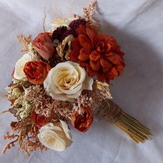 a bridal bouquet with red and white flowers on a white tableclothed surface