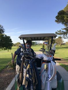 a man standing next to a golf cart filled with golf clubs and bags on top of it