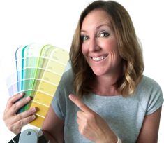 a woman pointing at the color swatches she is holding in her right hand and showing