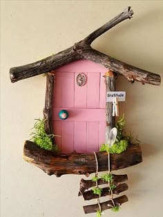 a small pink house made out of branches and wood with moss growing on the roof