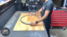 a man working on a piece of wood with a circular sawtoothing machine in the background