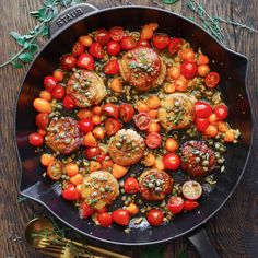 a pan filled with tomatoes and meatballs on top of a wooden table