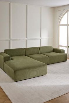 a large green couch sitting on top of a white rug