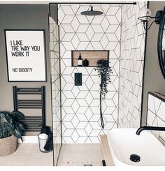 a bathroom with black and white tiles on the walls, a shower head, and a mirror