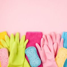 several different colored gloves and cleaning cloths on a pink background