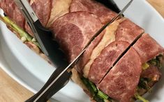 a sandwich cut in half sitting on top of a white plate next to a knife and fork