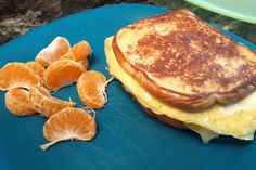 an egg and cheese sandwich with oranges on a blue plate