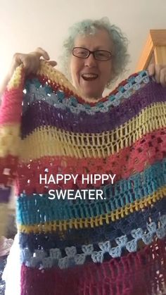 an older woman holding up a colorful crocheted blanket with the words happy hippy sweater on it