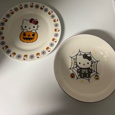 two plates with hello kitty designs on them sitting next to each other in front of a white wall