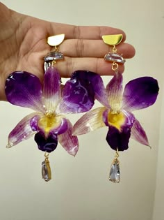 Introducing my orchid earrings - crafted from preserved, dried, purple orchids encased in resin, adorned with gold-plated studs and charming light purple accents. Handmade with love, using high-quality resin. The earrings are crafted with gold-plated copper alloy and adorned with sparkling light purple glass. Measuring 4 inches in length and 2.5-3 inches in width, each orchid carries a unique touch as they are made from real orchid flowers. Experience timeless elegance with these captivating ear Dope Jewelry Accessories, Orchid Earrings, Gold Orchid, Orchid Flowers, Purple Accents, Purple Orchids, Dope Jewelry, Funky Jewelry, Jewelry Lookbook