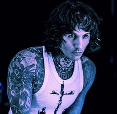 a man with tattoos and piercings on his arm is looking at the camera while wearing a tank top