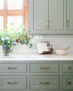 a kitchen with green cabinets and white counter tops