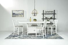 a white dining table with four chairs and a bench next to it on a rug