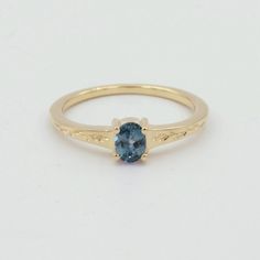 a gold ring with a blue topazte stone in the center, on a white background