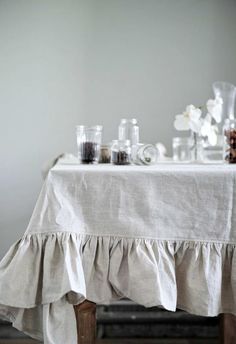 a table topped with jars filled with liquid and flowers sitting on top of a wooden chair