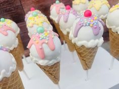 ice cream cones with sprinkles and toppings are arranged in rows on display