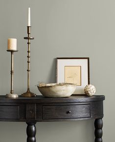 a wooden table with a bowl and two candles on it next to a framed photograph