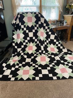 a black and white quilt sitting on top of a floor next to a tv set