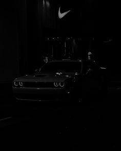 a black and white photo of a car in the dark with a person standing next to it