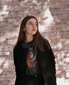 a woman standing in front of a brick wall