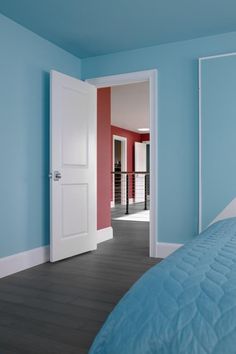 an open door leading to a bedroom with blue walls and wood flooring on the other side