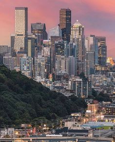 the city skyline is lit up at night, with skyscrapers in the foreground