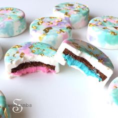 there are many decorated donuts on the white table with blue and pink frosting