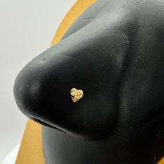 a black mannequin head with a gold heart on it