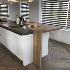 a kitchen with white cabinets and black counter tops next to a window covered in blinds