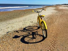 a yellow bike parked on the beach next to the ocean