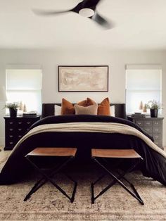 a black and white bed in a bedroom with two wooden chairs next to it on an area rug