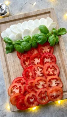 tomatoes and mozzarella are arranged on a cutting board with lights in the background