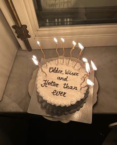 a birthday cake with lit candles sitting on top of a table