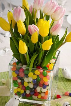 a vase filled with lots of candy and tulips on top of a table