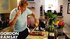 a man standing in a kitchen cutting up food on top of a wooden countertop