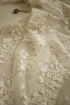 an embroidered fabric with white flowers on it and a flower pin in the middle of the photo