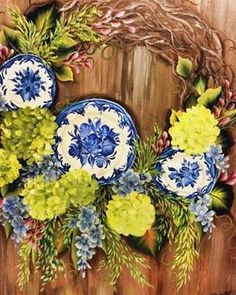 a painting of blue and yellow flowers on a wooden background with green leaves in the center