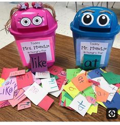 two plastic trash cans sitting on top of a wooden table covered in cut out letters