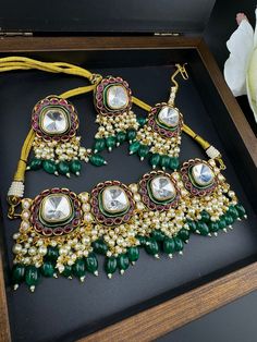 This is a trending jewelry piece This is a gorgeous modern Green and Ruby Premium quality Amrapali fusion in Pachi kundan and Italian Mina Jadau choker necklace with  moissanite Polki kundan with all natural multicolor stones and matching earrings and Tika is very unique. This is a modern style bridal set. This is so beautiful to look at and a perfect one for Bridal wear and party wear. Color : gold, Ruby and Green Necklace length :  (choker necklace length) Necklace width : 2.5 Inch Earring len Jadau Choker, Kundan Choker Necklace, Necklace Set With Earrings, Premium Jewelry, Trending Jewelry, Kundan Choker, Length Necklace, Choker Necklace Set, Wedding Jewellery Necklace