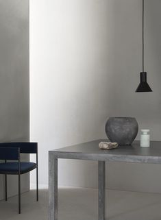 two chairs and a table with a vase on it in front of a white wall