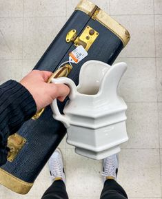 a person holding a coffee cup in front of a suit case