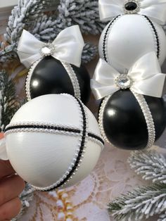 two black and white ornaments with bows on them are being held by someone's hand