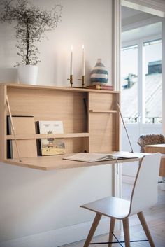 a wooden desk with a book shelf above it and a white chair next to it