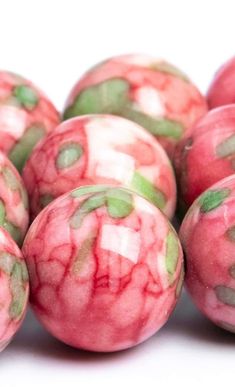 some pink and green marble balls on a white surface, with small green dots in the middle