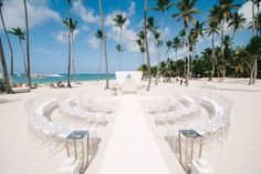 an empty beach with white chairs and palm trees