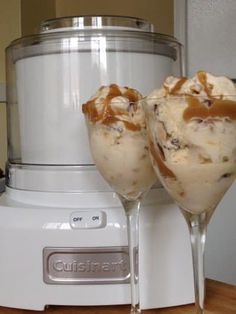 two glasses filled with ice cream sitting on top of a counter next to a blender