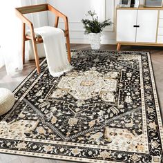 a black and beige area rug with an ornate design on the center, in front of a white chair