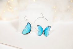 "Perfect for nature lovers who want to add a touch of whimsy to their everyday look. Each earring features a delicate faux butterfly in a beautiful shade of blue, intricately handcrafted to bring out its unique details. The hoops are made of high-quality materials that are comfortable to wear and won't cause any irritation. These earrings are perfect for everyday wear or special occasions and will make a great addition to any jewelry collection. Whether you're looking for a unique gift for a lov Blue Hoop Earrings As Summer Gift, Blue Hoop Earrings As A Summer Gift, Blue Hoop Earrings For Summer Gift, Blue Handmade Minimalist Hoop Earrings, Handmade Minimalist Blue Hoop Earrings, Minimalist Handmade Blue Hoop Earrings, Butterfly Hoop Earrings, Bridal Musings, Statement Earring